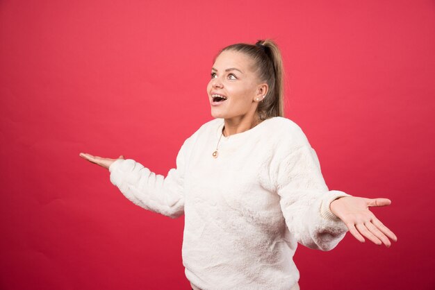 Porträt einer jungen Frau, die auf einer roten Wand steht und aufwirft