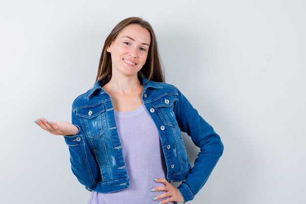 Porträt einer jungen Frau, die in T-Shirt, Jacke und fröhlicher Vorderansicht posiert