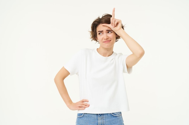 Porträt einer jungen Frau, die sich über jemanden lustig macht, der ein Verliererzeichen auf der Stirn zeigt und arrogant aussieht