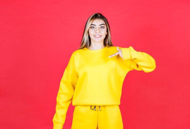 Porträt einer jungen Frau im gelben Outfit, die auf irgendwo zeigt