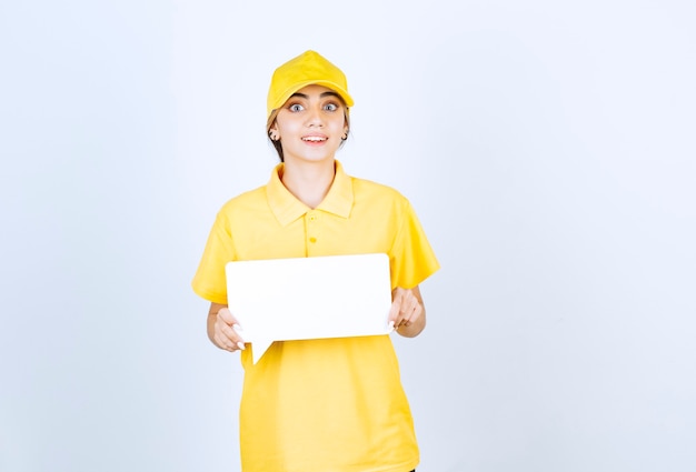 Porträt einer jungen Frau in gelber Uniform mit einer leeren Sprechblase.