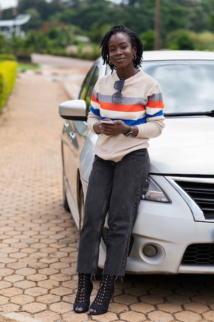 Kostenloses Foto porträt einer jungen frau mit afro-dreadlocks, die mit dem auto posiert