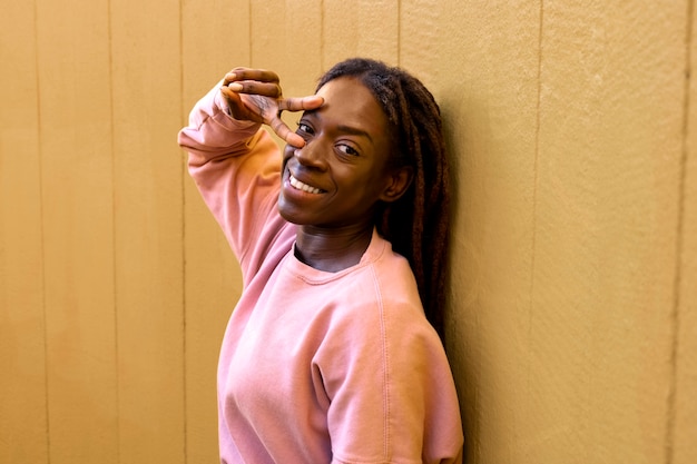 Porträt einer jungen Frau mit Afro-Dreadlocks, die posiert und ein Friedenszeichen zeigt