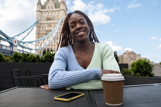 Porträt einer jungen Frau mit Afro-Dreadlocks in der Stadt, die Kaffee trinkt