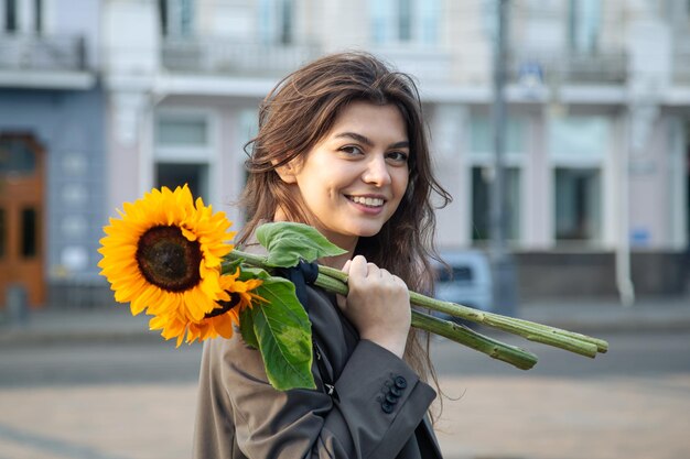 Porträt einer jungen Frau mit einem Strauß Sonnenblumen in der Stadt