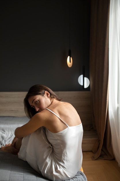 Porträt einer jungen Frau mit geringem Selbstwertgefühl, die zu Hause im Bett sitzt