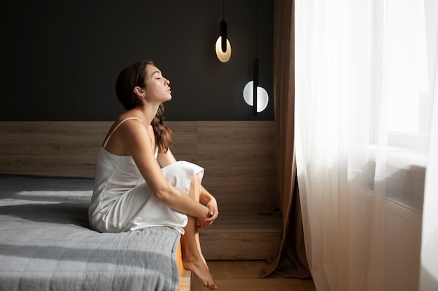 Porträt einer jungen Frau mit geringem Selbstwertgefühl, die zu Hause im Bett sitzt