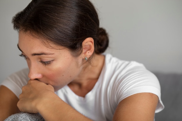 Porträt einer jungen Frau mit geringem Selbstwertgefühl, die zu Hause im Zimmer sitzt