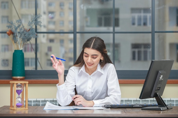Porträt einer jungen Geschäftsfrau, die am Schreibtisch sitzt und ihr Notizbuch liest