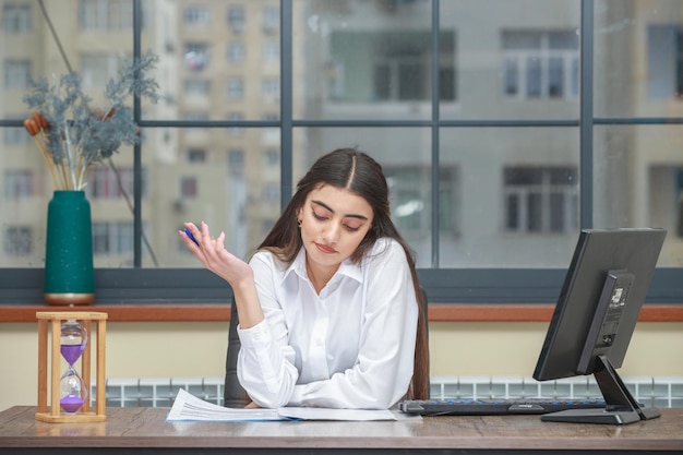 Porträt einer jungen Geschäftsfrau, die am Schreibtisch sitzt und ihre Notizen liest