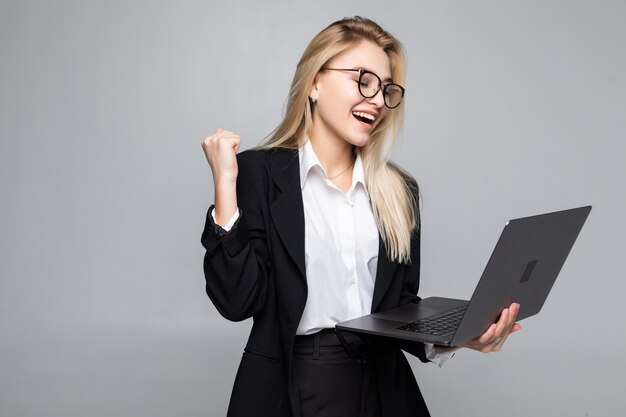 Porträt einer jungen glücklichen Geschäftsfrau mit einem Laptop mit Gewinngeste