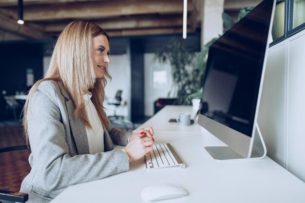 Porträt einer jungen intelligenten Geschäftsfrau, die an ihrem Arbeitstisch im Büro sitzt