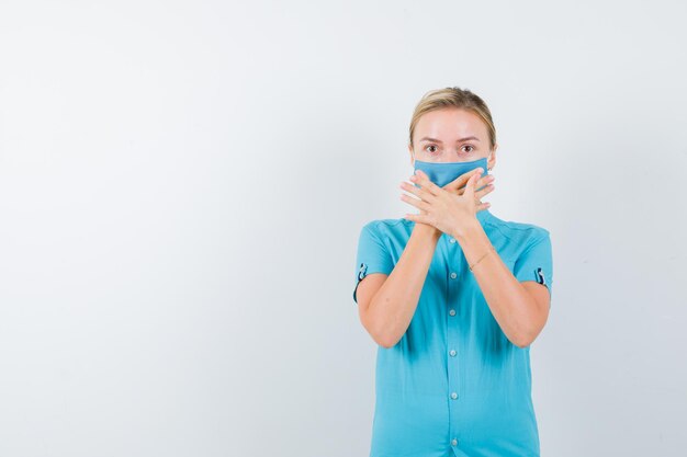 Porträt einer jungen Ärztin, die den Mund mit den Händen in Uniform bedeckt, isoliert