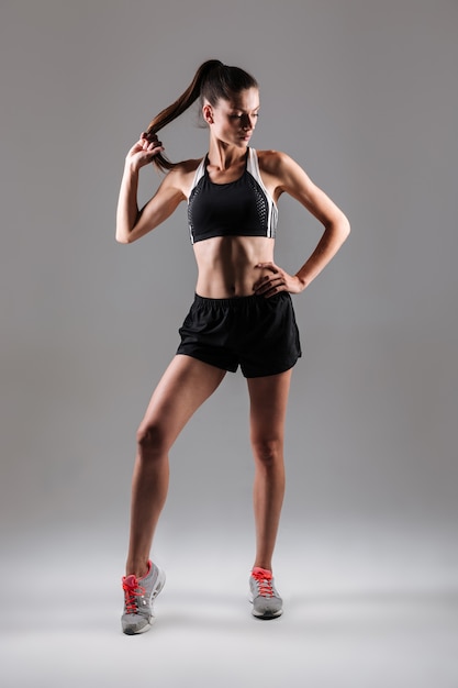 Porträt einer jungen schlanken Fitnessfrau, die im Stehen aufwirft