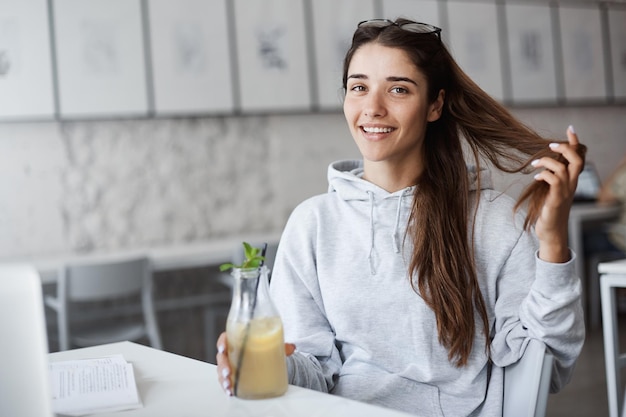 Kostenloses Foto porträt einer jungen, sorglosen frau, die limonade trinkt und sich weniger um ihr studium kümmert, um im urlaub einkaufen zu gehen