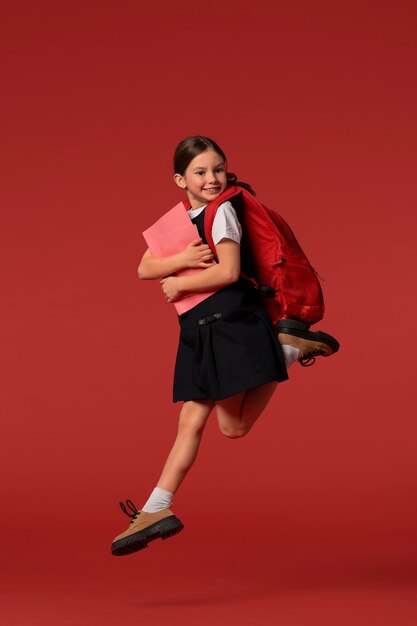 Porträt einer jungen Studentin in Schuluniform, die in der Luft springt
