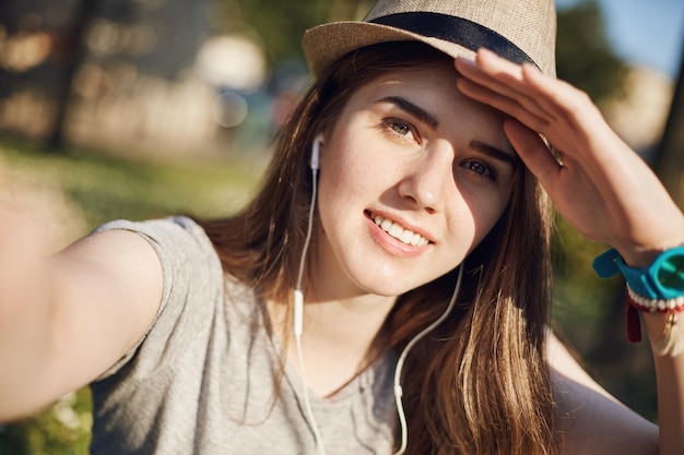 Kostenloses Foto porträt einer jungen touristin oder studentin, die an einem sonnigen tag ein selfie macht und von fernen orten träumt reisestudienkonzept