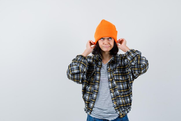 Porträt einer kleinen Frau, die Mütze in T-Shirt-Jackenmütze zieht und unzufrieden aussieht