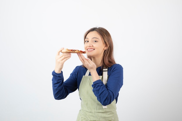 Porträt einer Köchin in Schürze, die Pizza hält und lächelt