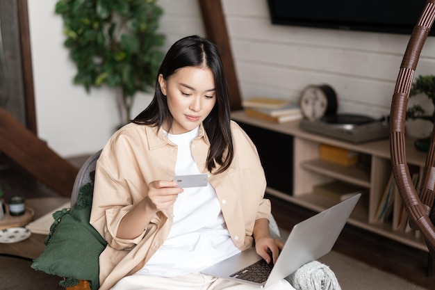 Porträt einer koreanischen Frau, die online auf der Website mit Laptop- und Kreditkartenkaufkurs kauft ...