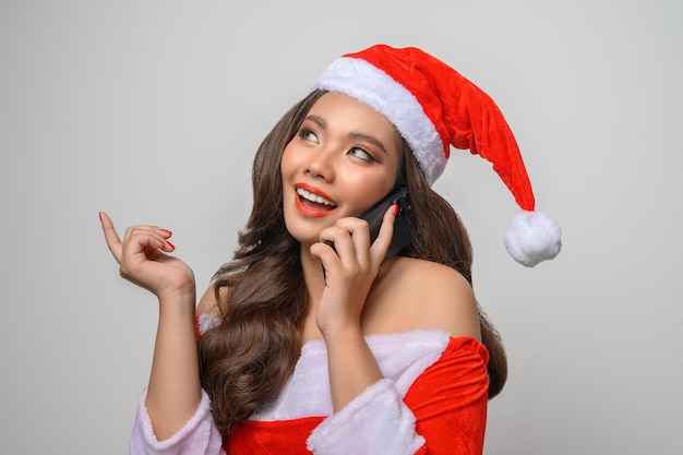 Porträt einer lächelnden Frau im roten Weihnachtsmann, die Smartphone zeigt