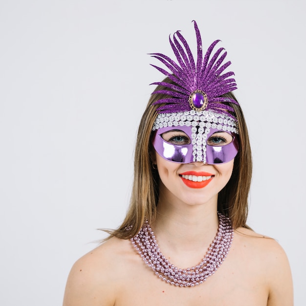 Kostenloses Foto porträt einer lächelnden frau in tragender halskette der karnevalsmaske vorbei auf weißem hintergrund