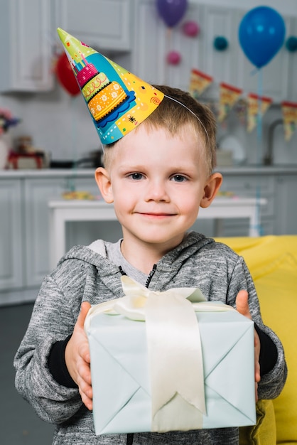 Porträt einer lächelnden Geburtstagsjungenholding wickelte Geschenkbox in der Hand ein