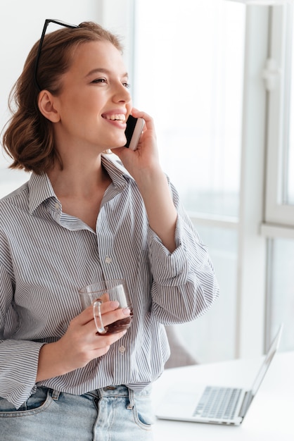 Porträt einer lächelnden jungen Frau, die auf Handy spricht