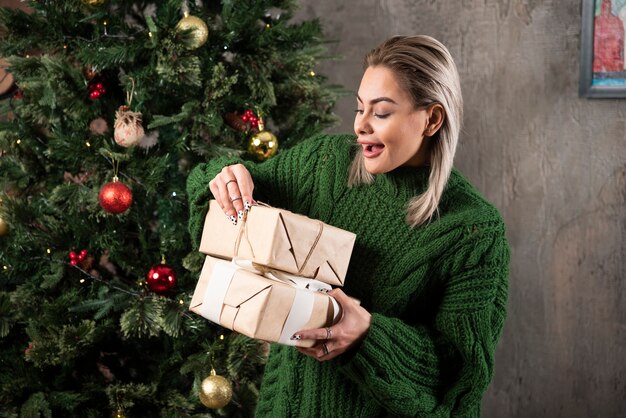 Porträt einer lächelnden jungen Frau, die Geschenke betrachtet