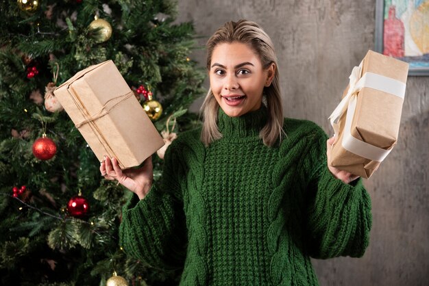 Porträt einer lächelnden jungen Frau, die Geschenke hält