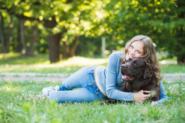 Porträt einer lächelnden jungen Frau, die ihren Hund im Garten liebt