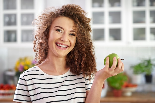 Porträt einer lächelnden jungen Frau mit einem Apfel