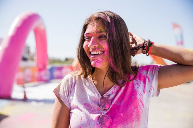 Porträt einer lächelnden jungen Frau mit holi Farbgesicht