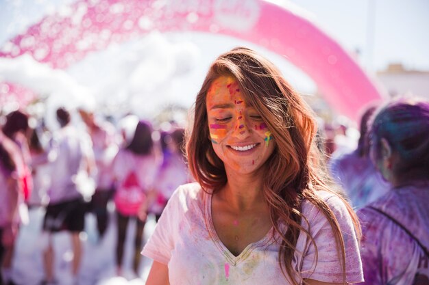 Porträt einer lächelnden jungen Frau mit holi Farbgesicht