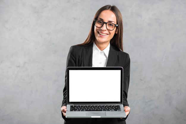 Porträt einer lächelnden jungen Geschäftsfrau, die Laptop mit leerer weißer Bildschirmanzeige zeigt