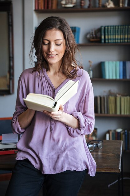 Porträt einer lächelnden lässigen reifen Frau, die Buch liest