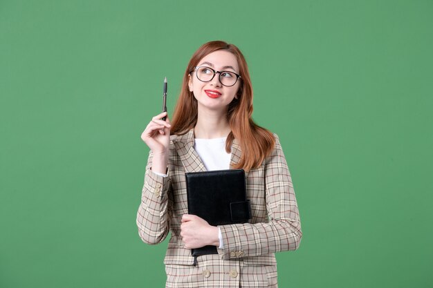 Porträt einer Lehrerin im Anzug mit Notizblock auf Grün