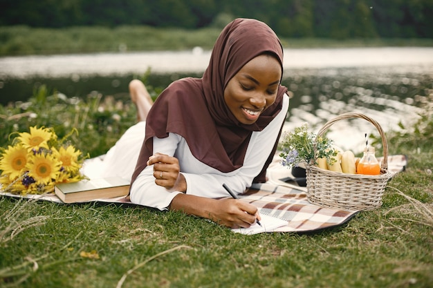 Porträt einer muslimischen Frau lag auf der karierten Picknickdecke in der Nähe des Flusses