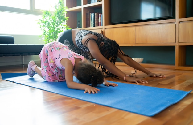 Porträt einer Mutter und Tochter, die Yoga-Übungen machen, während sie zu Hause bleiben. Sportkonzept