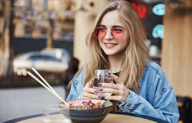 Porträt einer natürlichen frau mit sonnenbrille, die asiatische speisen bei s genießt