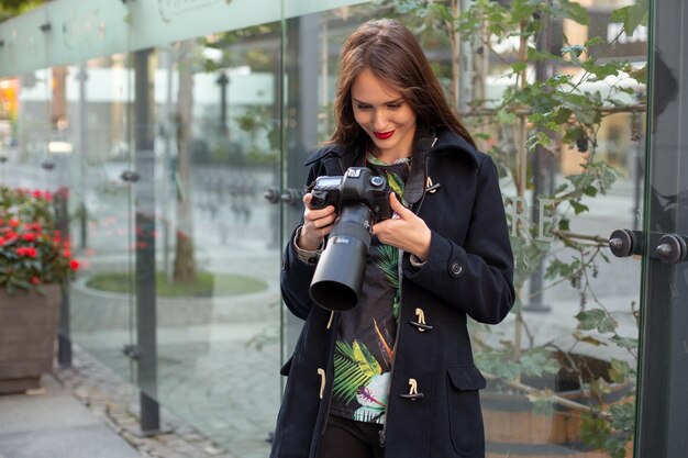 Porträt einer professionellen Fotografin auf der Straße, die mit einer Kamera fotografiert. Fotoshooting Fotoshooting in der Stadt