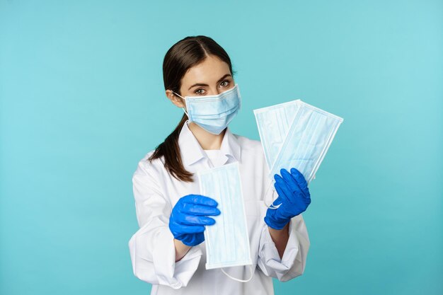 Porträt einer Ärztin im medizinischen Bereich, die Gesichtsmasken vorschlägt, die vor einer Covid-Pandemie im Krankenhaus stehen