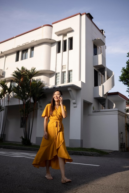 Porträt einer schönen asiatischen Frau, die in der Stadt posiert, während sie ein gelbes Kleid trägt
