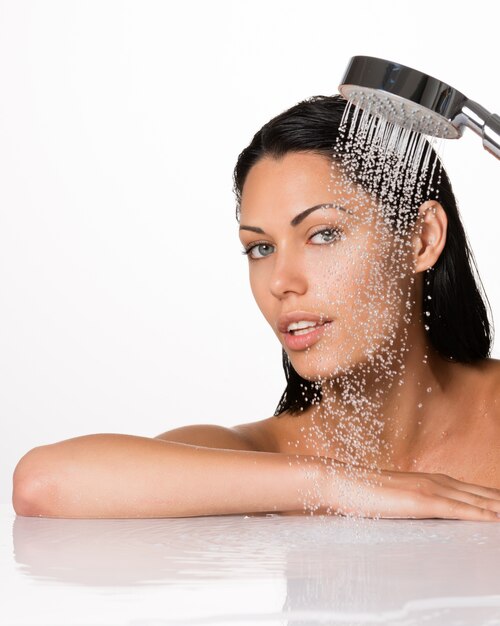 Porträt einer schönen brünetten Frau hält Dusche in Händen mit fallendem Wasser
