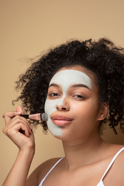 Porträt einer schönen Frau, die Gesichtsmaske mit einem Make-up-Pinsel auf ihrem Gesicht aufträgt