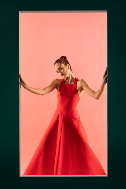 Porträt einer schönen Frau, die in einem fließenden roten Kleid mit Kopienraum posiert
