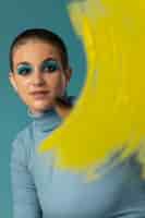 Kostenloses Foto porträt einer schönen frau, die in einem rollkragenpullover mit gelbem pinselstrich posiert