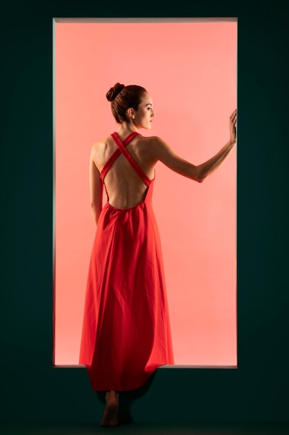 Porträt einer schönen Frau, die mit einem fließenden roten Kleid posiert
