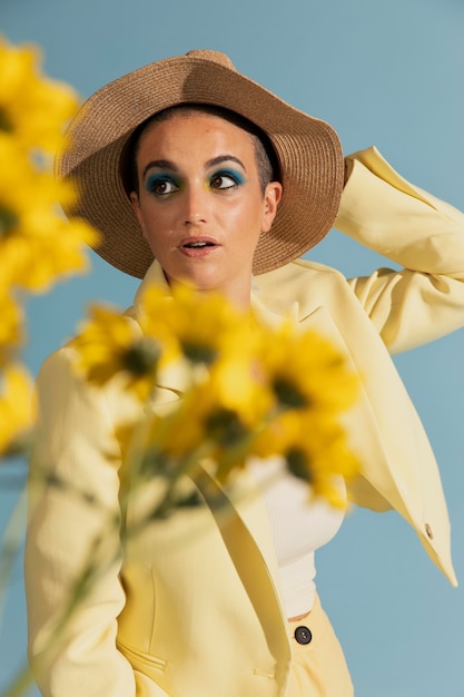 Kostenloses Foto porträt einer schönen frau, die mit einer gelben jacke und blumen posiert