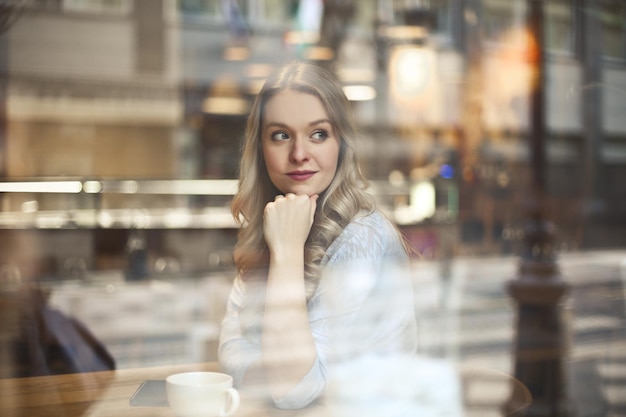 Porträt einer schönen Frau durch ein Glas eines Cafés